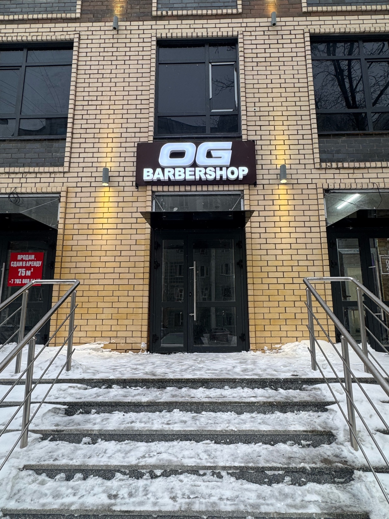 Вход в OG Barbershop с вывеской OG над дверью
